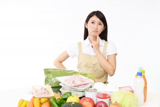 たくさんの食品を前に考えている女性